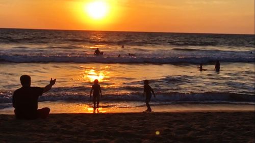 Silhouette of people at beach during sunset