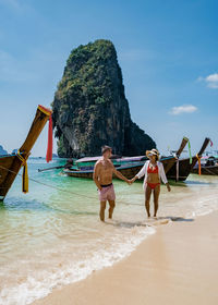 Rear view of men on beach against sky