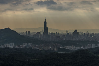 Buildings in city against cloudy sky