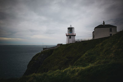 Lighthouse by sea against sky
