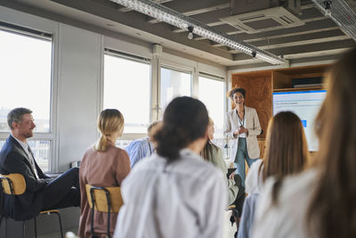 Female entrepreneur giving presentation to colleagues in educational event at office