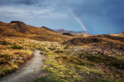 Scenic view of rainbow over mountain against sky