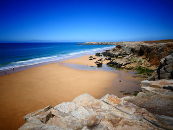 Scenic view of beach against clear blue sky