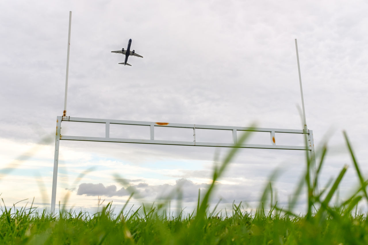 LOW ANGLE VIEW OF AIRPLANE FLYING OVER FIELD