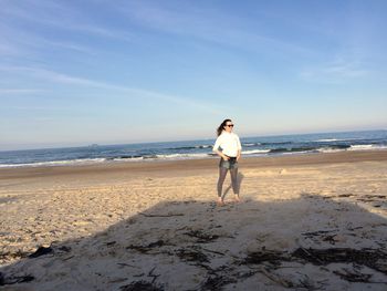 Full length of woman standing at beach against sky