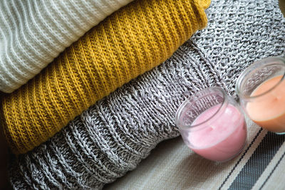Close-up of tea light candles by stacked sweaters on table