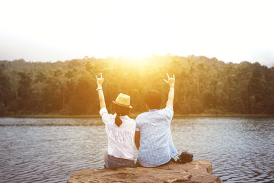 Woman sitting by lake against clear sky