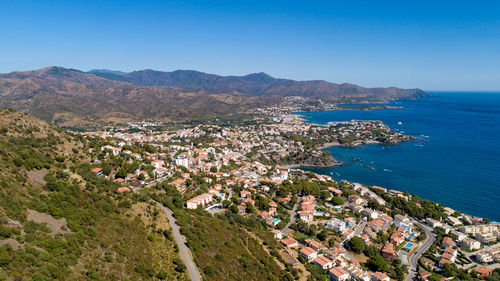 High angle view of townscape by sea against blue sky