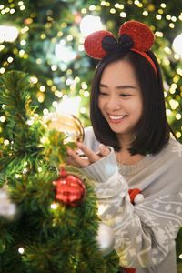Portrait of young woman standing by christmas tree