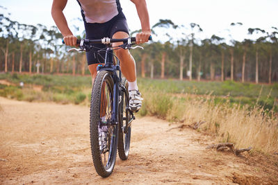 Low section of man riding bicycle on field