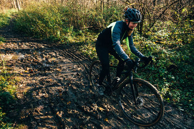 Man riding bicycle on field in forest