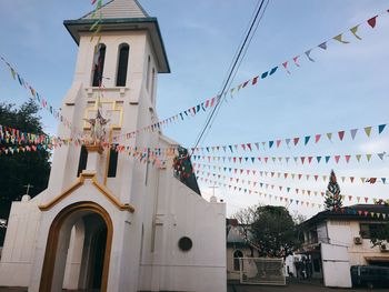 Low angle view of flags hanging outside building against sky