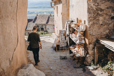 Rear view of people walking by buildings in city