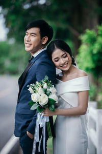 Happy couple standing against plants