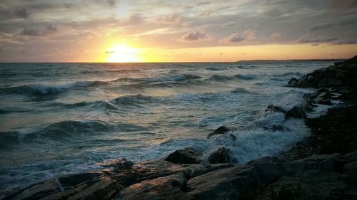 Scenic view of sea against dramatic sky during sunset