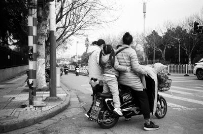 Rear view of people riding motorcycle on road