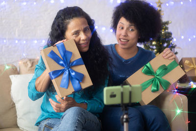 Mother and daughter showing gift box while video conferencing