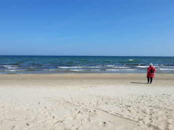 Rear view of man on beach against clear sky