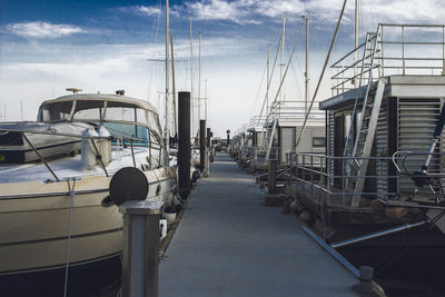 Sailboats moored at harbor against sky