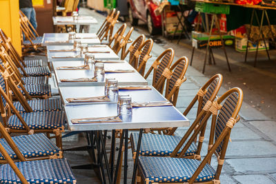 Empty chairs and tables at sidewalk cafe