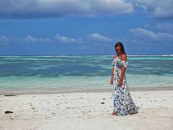 Woman standing at beach against sky