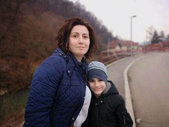 Portrait of mother and son standing in city