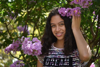 Portrait of smiling teenage girl standing amidst purple flowers
