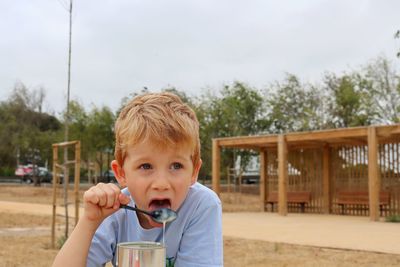 A blond boy licks a spoonful of condensed milk. a five-year-old boy is eating sweet milk. 