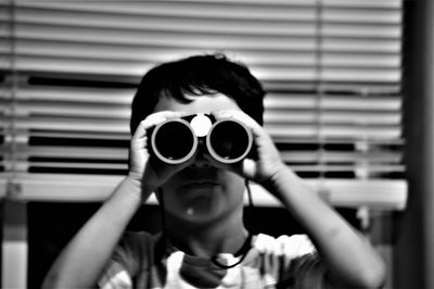 Boy looking through binoculars against window