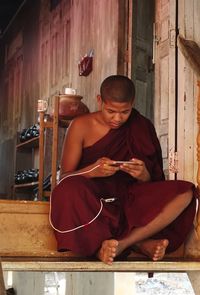 Young man using mobile phone while sitting at home