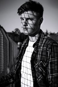 Young man standing in sunlight against sky