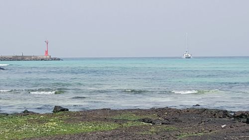 Sailboat in sea against clear sky
