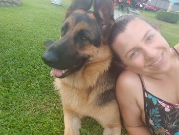 Portrait of young woman with dog on grass