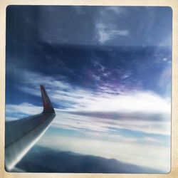 Cropped image of airplane flying over clouds in sky