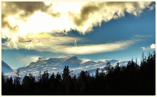 Scenic view of snowcapped mountains against cloudy sky