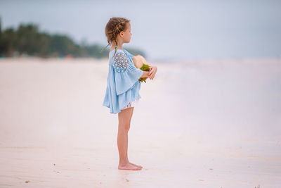Side view of young woman standing at beach