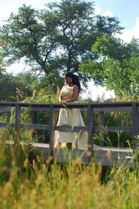 Woman sitting on grass against trees