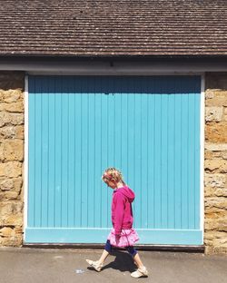 Rear view of girl standing in front of house