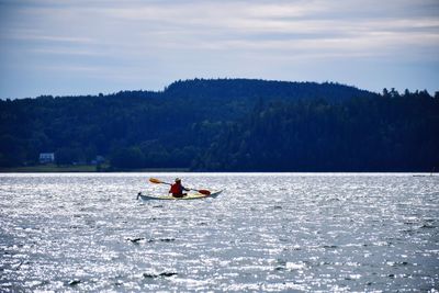 Woman boating on river against sky