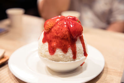 Strawberry bingsu or shaved ice dessert topped with strawberry sauce and fresh strawberry