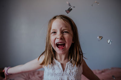 Portrait of young girl happily throwing silver confetti