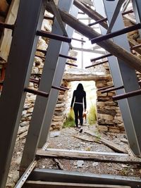 Rear view of woman walking by building