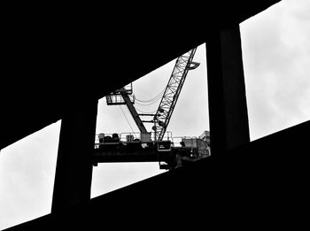 Low angle view of silhouette cranes against sky