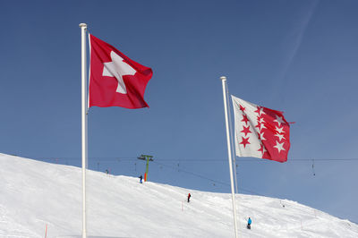 Low angle view of flag flags on snowcapped mountain against sky