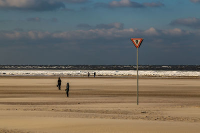 People walking on beach against sky