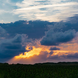 Scenic view of dramatic sky over land during sunset