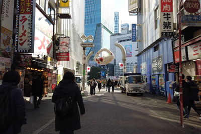 People walking on street amidst buildings in city