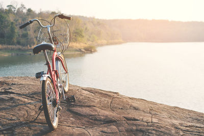 Bicycle by water against sky