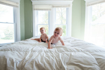Rear view of mother and daughter on bed
