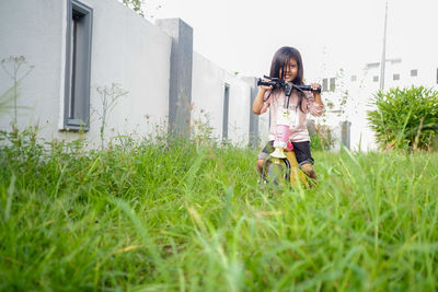 Girl playing scooter with green grass background 